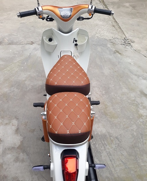 Yên xe được thiết kế tách rời trước sau và bọc da PU với họa tiết quả trám phối kết hợp hai màu nâu sẫm và vàng bò